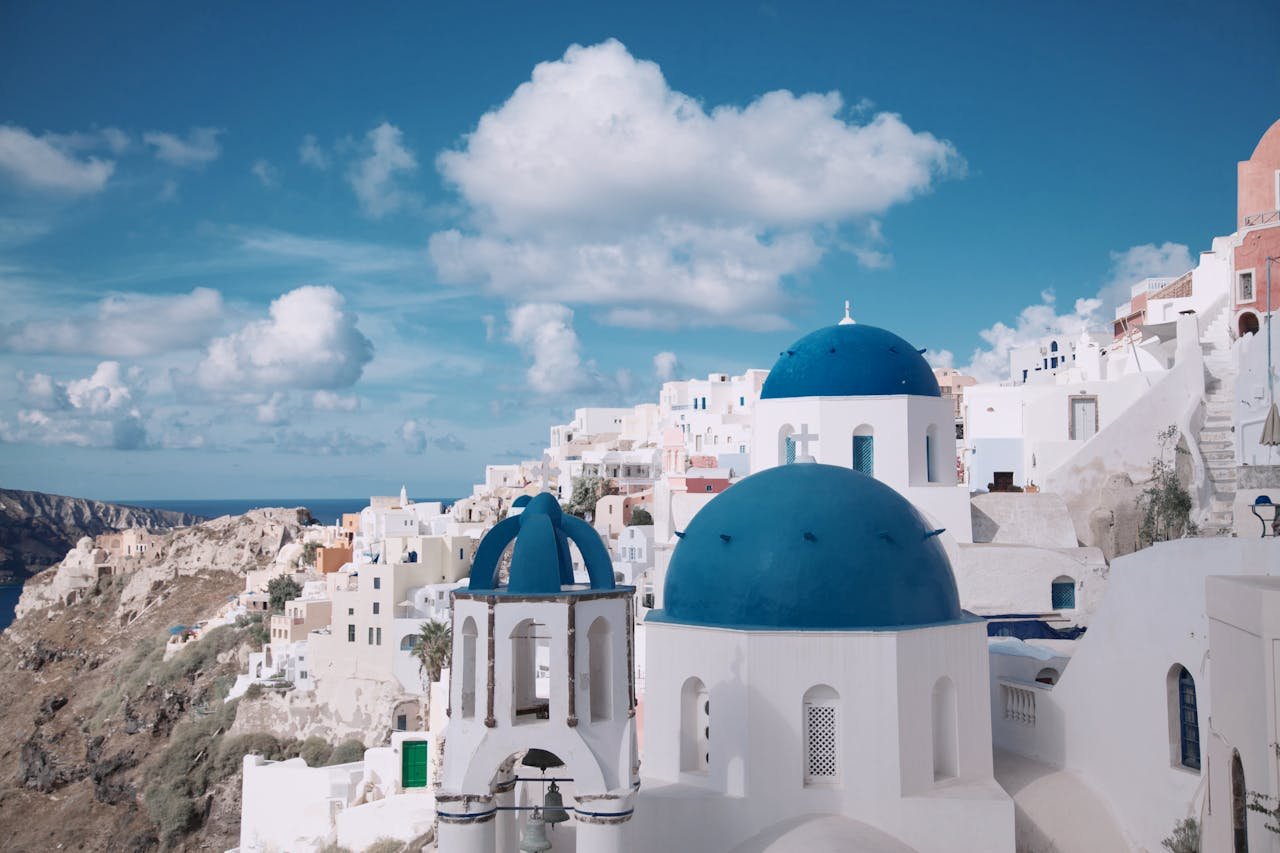 Breathtaking view of Oias iconic blue-domed churches against a vibrant sky in Santorini, Greece.