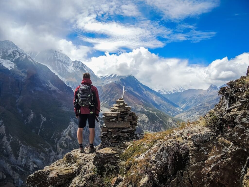man standing on top of mountain beside cairn stones 48nerzqchgo